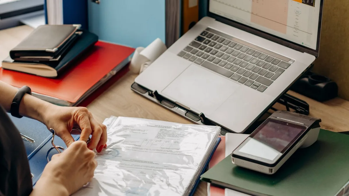 Mujer organizando la documentación de la empresa junto a un portátil