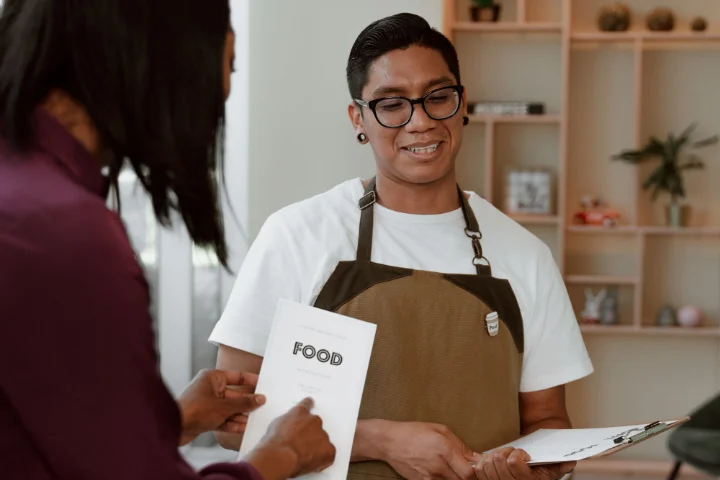 Camarero tomando nota a unos clientes con la carta