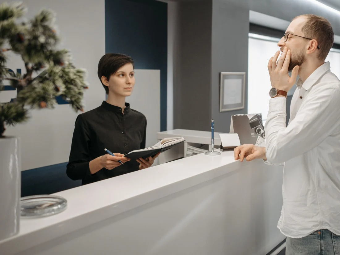 Recepcionista de una clínica dental atendiendo a un paciente