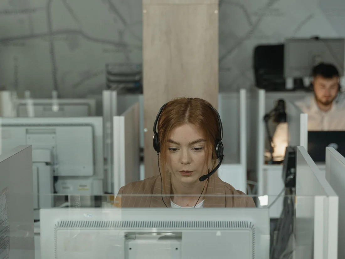 Agente de atención al cliente con auriculares apoyada por un chatbot con IA