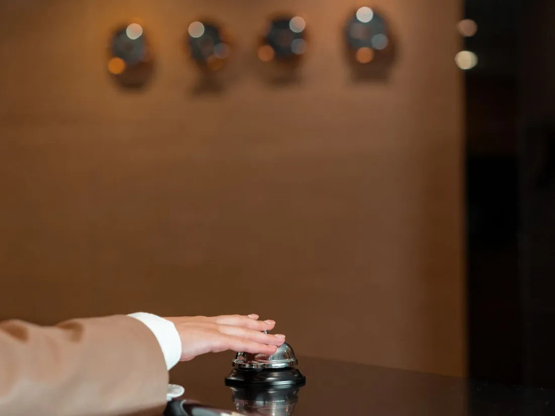 Huésped llamando al timbre de la recepción de un hotel
