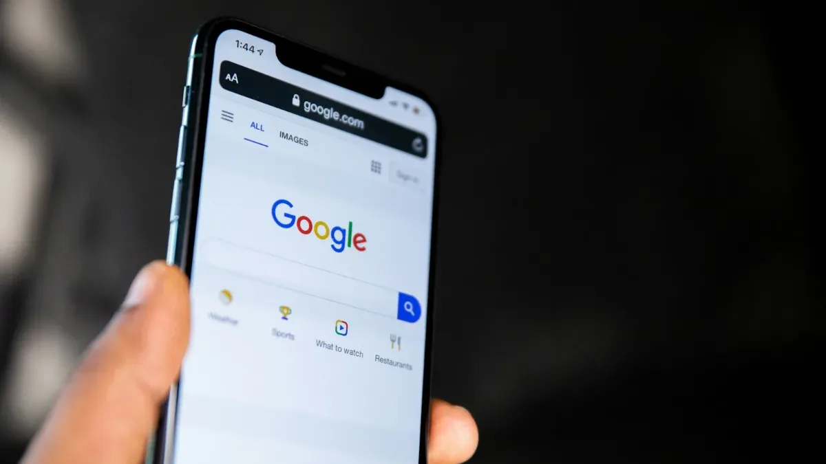 Mano sosteniendo un móvil con la página de inicio del buscador de Google