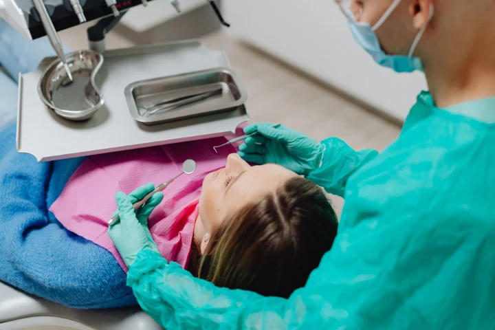 Dentista revisando la boca de una niña en la consulta
