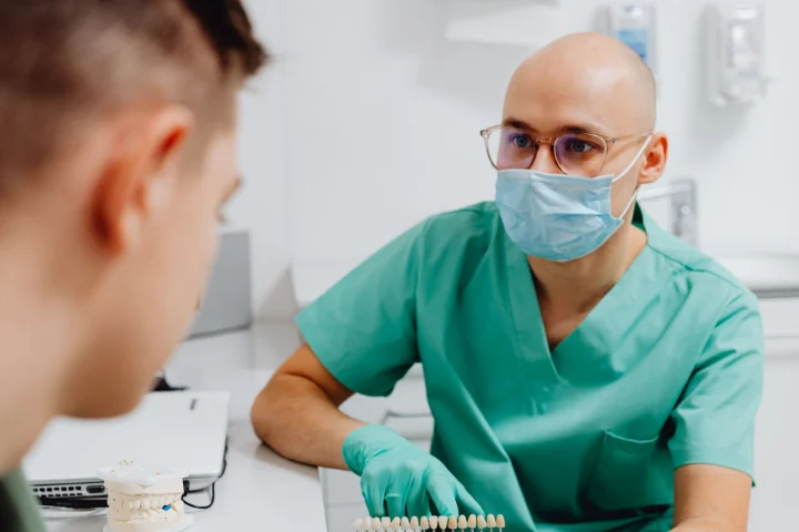 Dentista explicando un tratamiento a un paciente en la primera visita