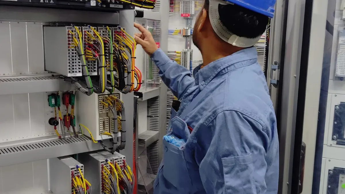 Técnico con casco revisando un cuadro de control industrial durante una revisión preventiva