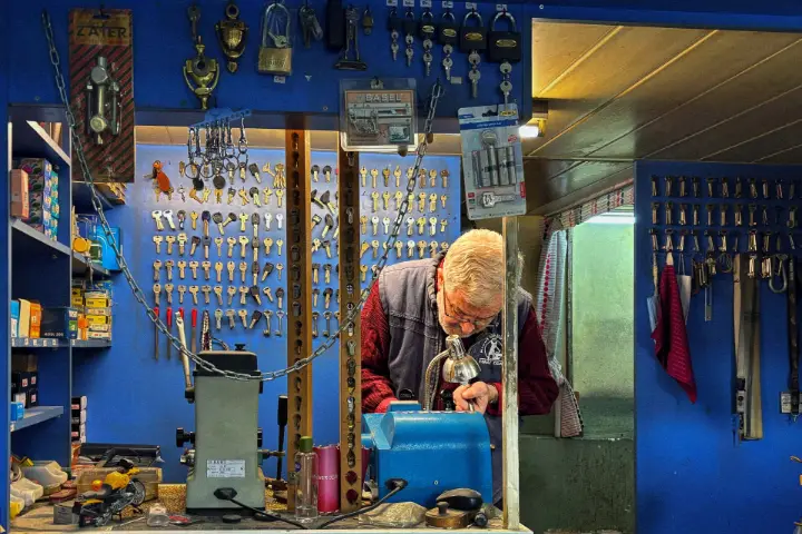 Cerrajero copiando una llave en su taller de cerrajería